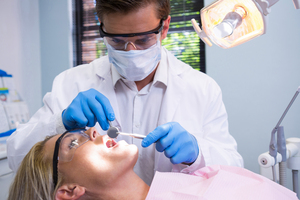 Dentist holding tools while examining woman at medical clinic Zahnentfernung Lörrach – Zahnarzt bei schonender Extraktion