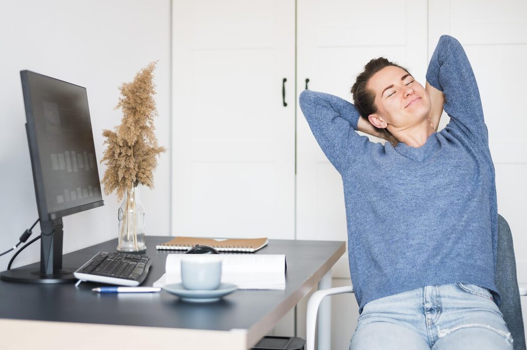 Entspannungspause am Schreibtisch Frau macht am Schreibtisch vor dem Monitor eine kurze Entspannungspause, eine einfache Hilfe gegen Zähneknirschen am Tag
