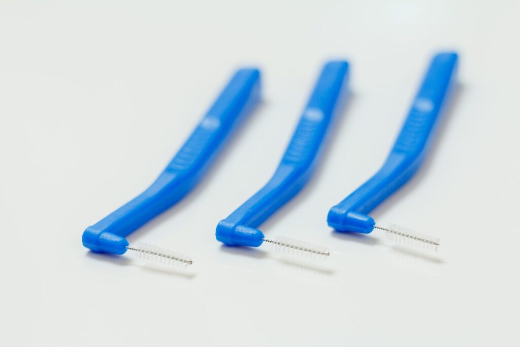 Abgewinkelte Interdentalbürsten Drei blaue abgewinkelte Interdentalbürsten auf weißem Untergrund für die Reinigung der Zahnzwischenräume