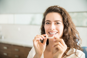 Beautiful Patient Holding Orthodontic Retainers In Dental Clinic Patientin zeigt transparente Invisalign-Schiene in der Zahnarztpraxis am Senser Platz
